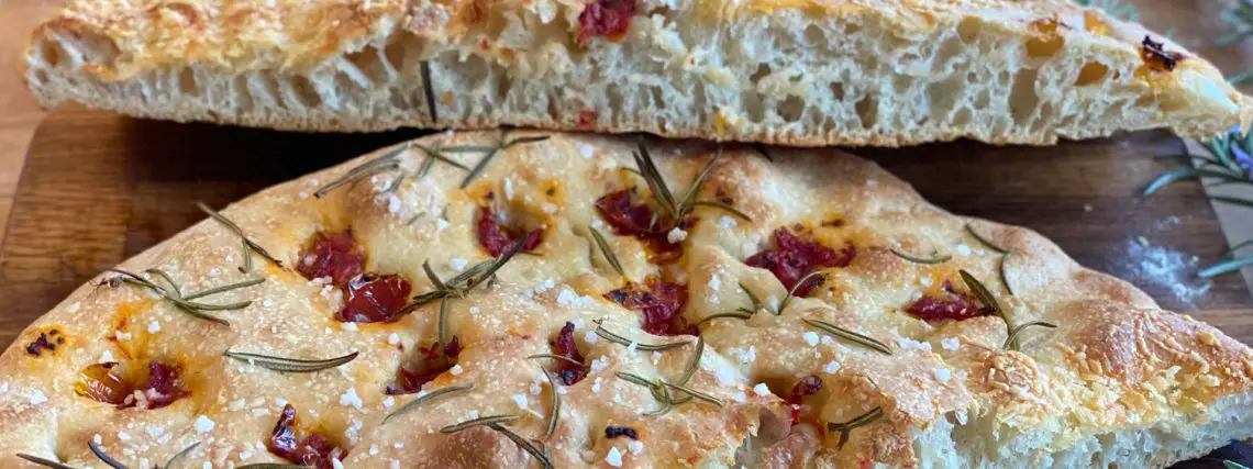 Focaccia Aufgeschnitten, fluffig Teig, große Porung, belegt mit Rosmarin und getrockneten Tomaten