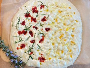 Focaccia Teig fertig belegt mit getrockneten Tomaten und Käse