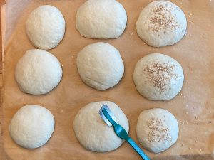 Milchbrötchen vor dem Backen mit Körnern versehen und einschneiden