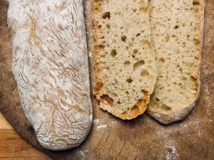 Ciabatta fertig gebacken. Fluffig, große Porung. Ganzes Ciabatta und aufgeschnitten.