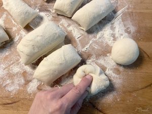 Pizzateig in gleiche Portionen eingeteilt. Schritt des Rundformens wird gezeigt.