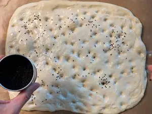 Fladenbrot mit Schwarzkümmel bestreuen