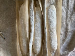Baguette-Teiglinge mit zugeschnittenem Backpapier ins Bäckerleinen legen