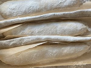 Baguette-Teiglinge mit zugeschnittenem Backpapier ins Bäckerleinen legen
