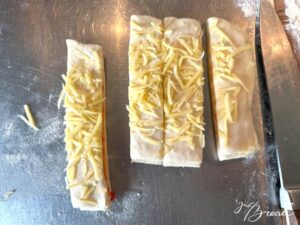 Knusperstangen: Nach Geschmack die Oberfläche leicht mit Wasser besprühen und mit geriebenem Käse bestreuen, oder diesen erst auf die gedrehten Stangen streuen.