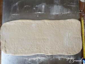 Teig für kleine Hörnchen ungefähr auf 50 x 20 cm ausrollen.