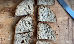 Saftiges Sauerteigbrot mit Saaten – gebacken mit 2-stufig geführtem Roggensauerteig für intensives Aroma und lange Frischhaltung. Knusprige Kruste, lockere Krume mit Sonnenblumenkernen, Sesam und Leinsamen. Perfekt als Pausenbrot, Sandwich oder Beilagenbrot. Ideal für eine ausgewogene Ernährung mit Vollkorn und gesunden Saaten.