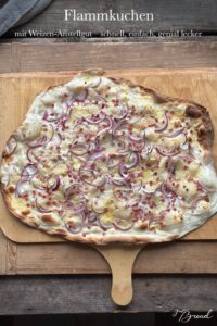 Frisch gebackener Flammkuchen mit knusprigem Sauerteigboden aus Weizen-Anstellgut, belegt mit Schmand, Schinkenwürfeln und Gruyère-Käse.