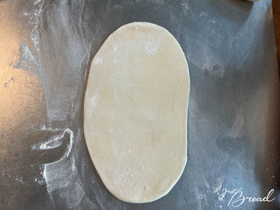 Flammkuchenteig erst länglich, dann in die Breite dünn ausrollen