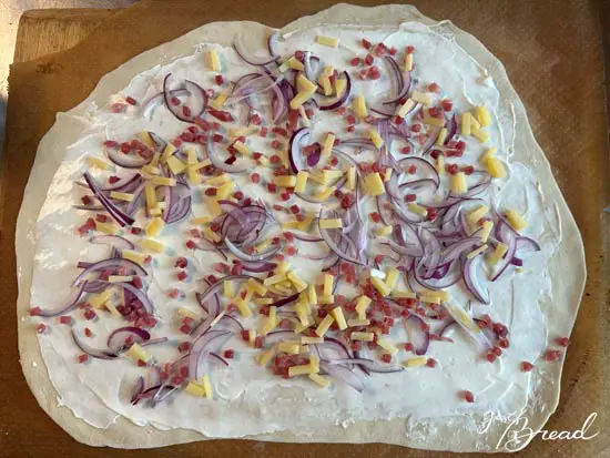 Elsässer Klassiker: Flammkuchen mit Creme fraiche, Zwiebeln, Schinkelnwürfeln und Gryere Käse
