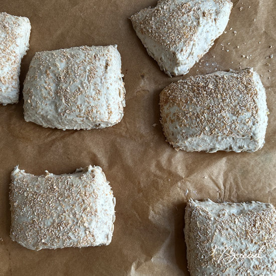 Abgestochene Weizenschrotbrötchen auf der Arbeitsfläche.