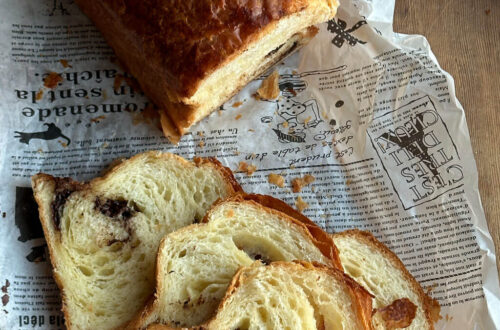 Mehrere Scheiben Schoko-Croissant-Toast mit blättriger Krume und schokoladigem Kern auf rustikalem Papier.