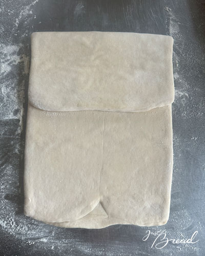 Der obere Teil des ausgerollten Teigs wird zur Mitte gefaltet, um die erste einfache Tour zu formen.