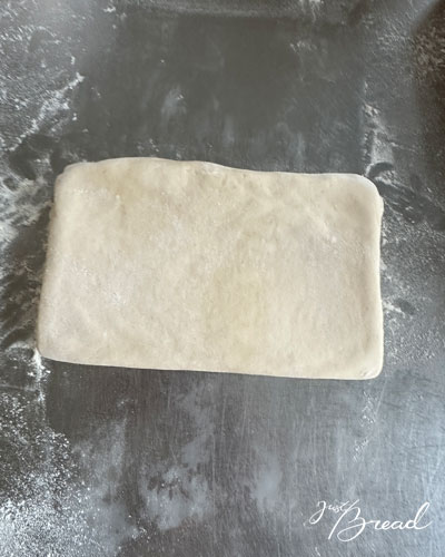 Gefalteter Teigblock nach der ersten einfachen Tour auf leicht bemehlter Arbeitsfläche.