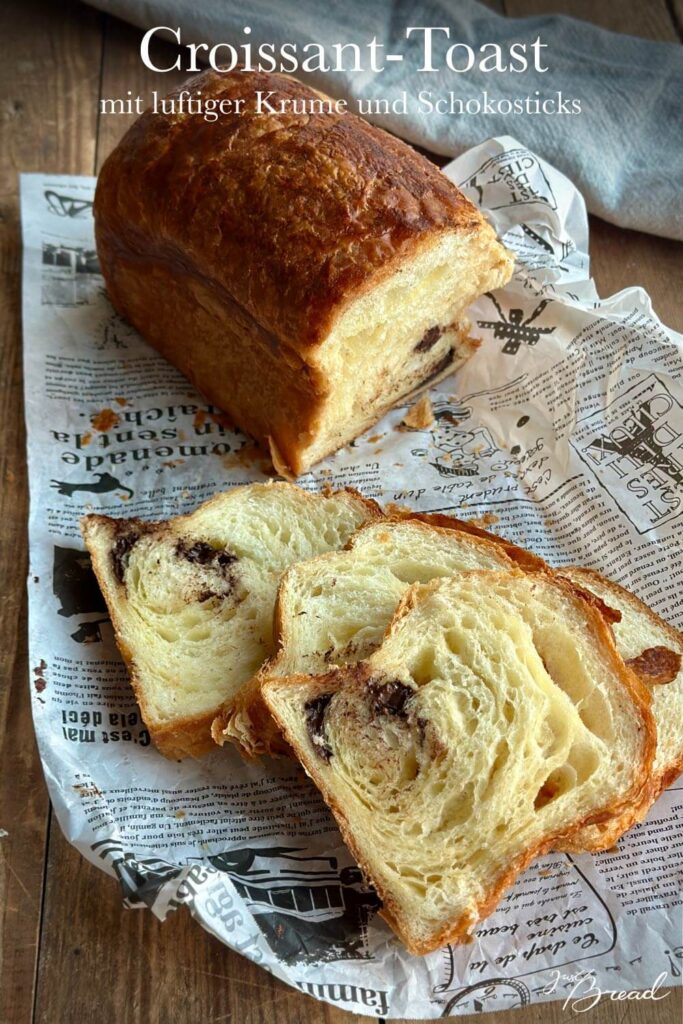 Gebackener Schoko-Croissant-Toast mit goldbrauner Kruste und mehreren angeschnittenen Scheiben auf einem Holztisch.