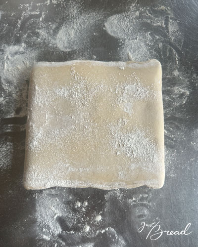 Eingeschlagener Teigblock liegt gedreht auf der Arbeitsfläche und ist bereit für die erste einfache Tour.