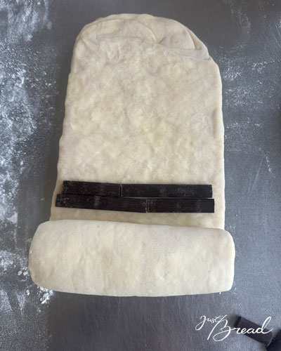 Teig ist bereits einmal über die erste Schokostick-Reihe geschlagen, zweite Reihe Schokosticks liegt darüber.