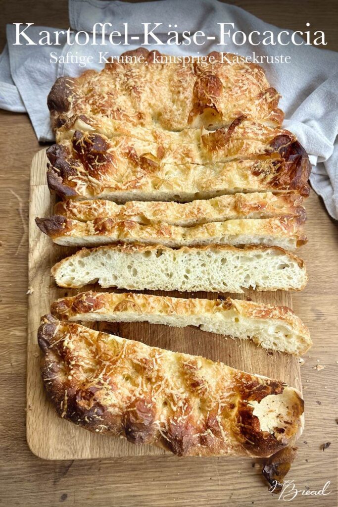Kartoffel-Käse-Focaccia in Streifen geschnitten auf einem Holzbrett, mit goldbraun gebackener Käsekruste