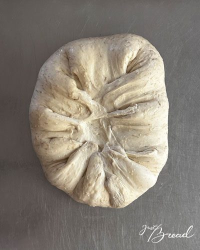 Focaccia-Teig, dessen Ränder locker zur Mitte gefaltet sind