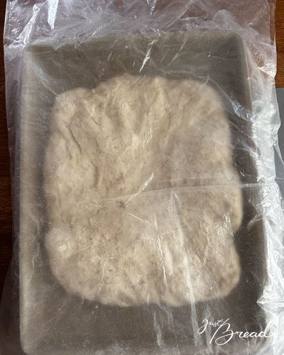 Mit Folie abgedeckter Focaccia-Teig im Ofenzauberer während der Stückgare