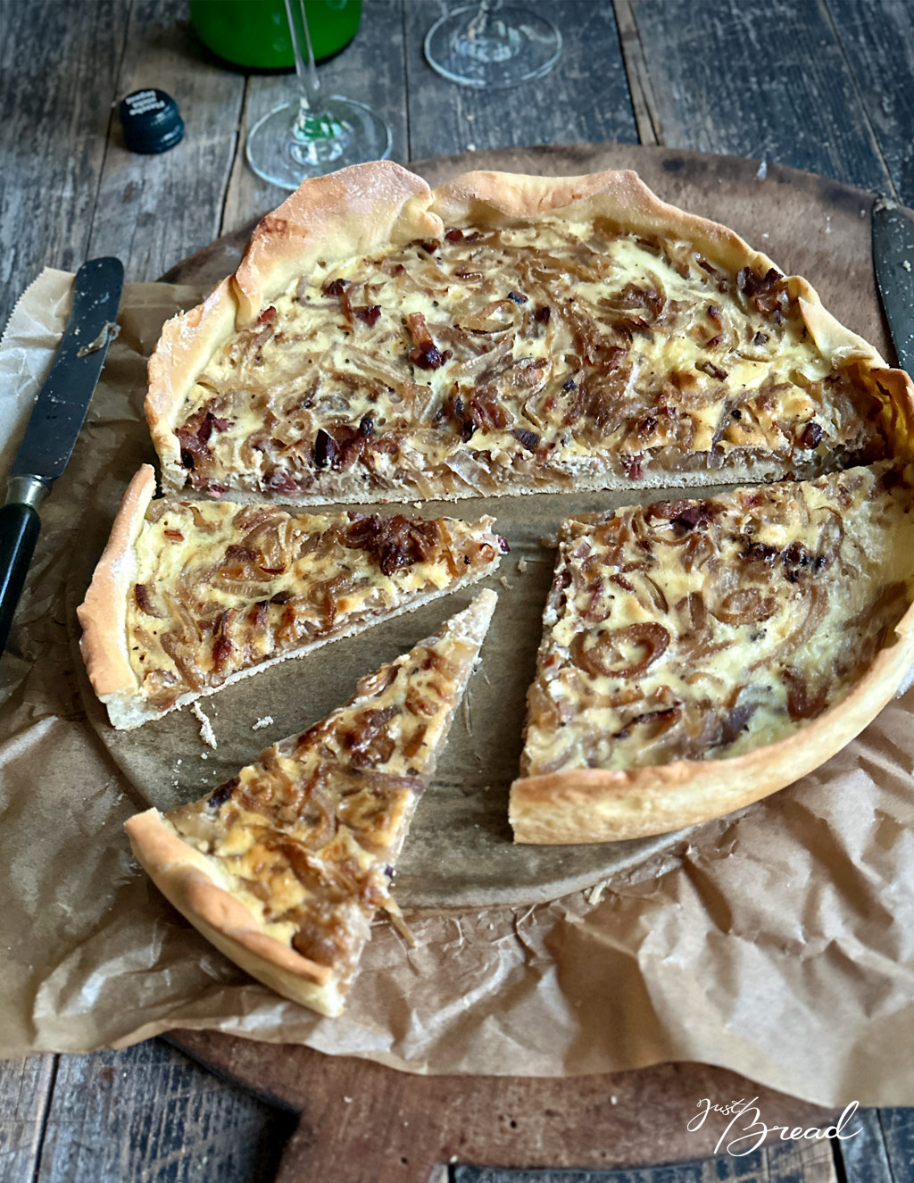Zwiebelkuchen in Stücken mit Federweißer im Hintergrund