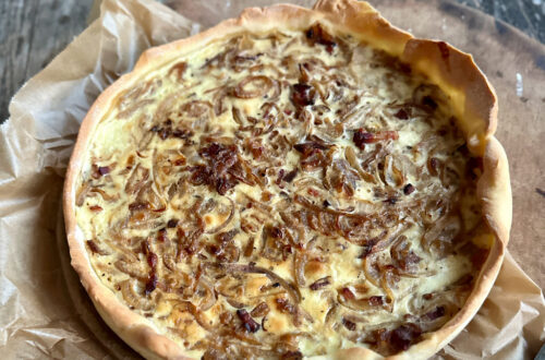 Zwiebelkuchen mit Hefeteig, frisch gebacken in der Springform auf einem Holzbrett
