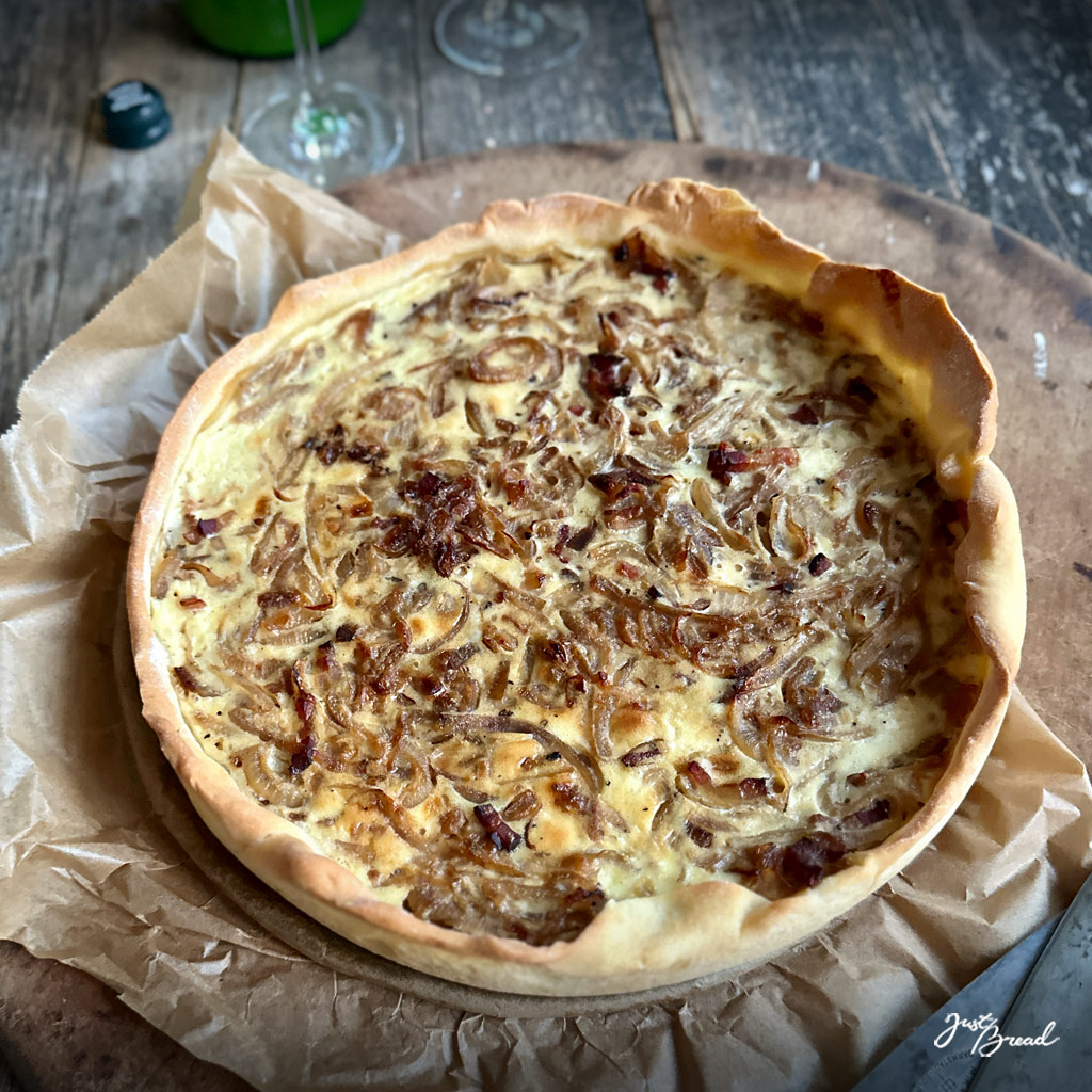Zwiebelkuchen mit Hefeteig, frisch gebacken in der Springform auf einem Holzbrett