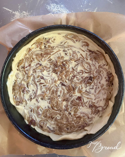 Zwiebelkuchen in der Springform mit Eier-Sahne-Guss vor dem Backen