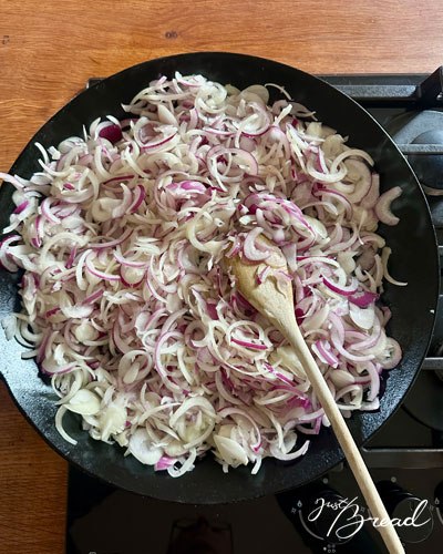 Zwiebelringe in der Pfanne dünsten für den Zwiebelkuchen
